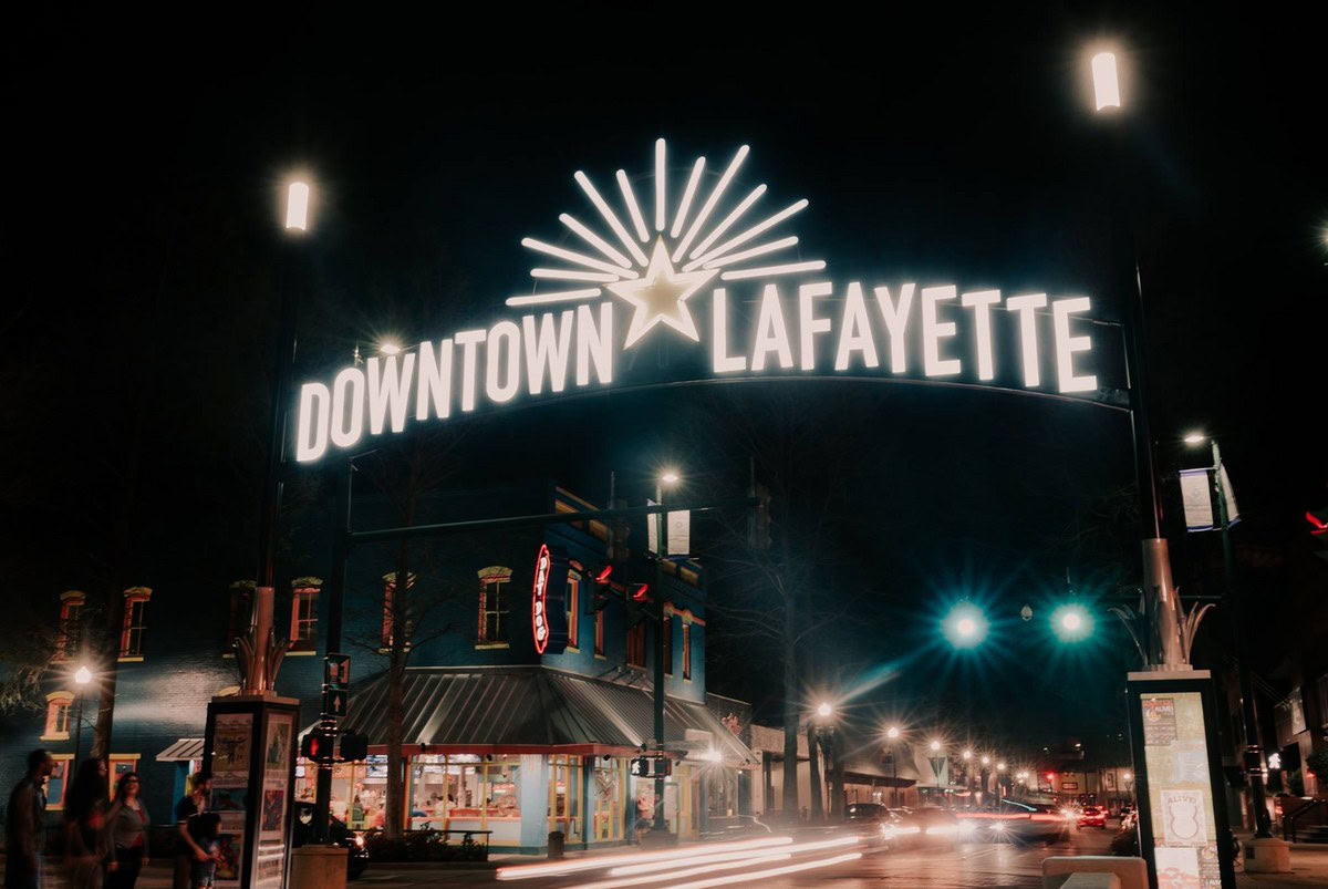 Vibrant night view of Lafayette's downtown area with illuminated signs and lively streets, showcasing the city's energetic atmosphere for new residents moving to Acadiana.