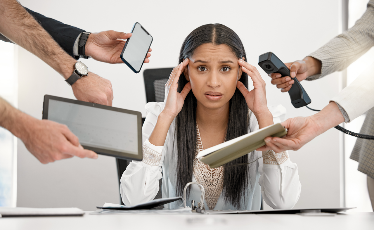 Woman overwhelmed by multiple property management devices and calls, illustrating the importance of choosing a reliable property management company.