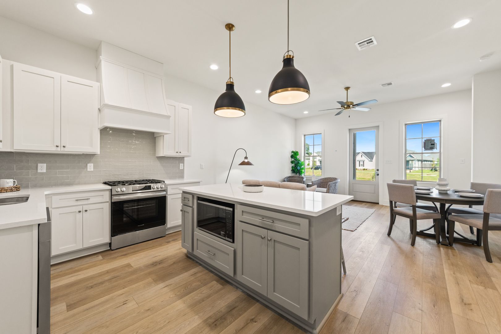 Bright and spacious kitchen with white cabinets, stainless steel appliances, and an island, seamlessly connected to a cozy living and dining space with large windows and scenic views.