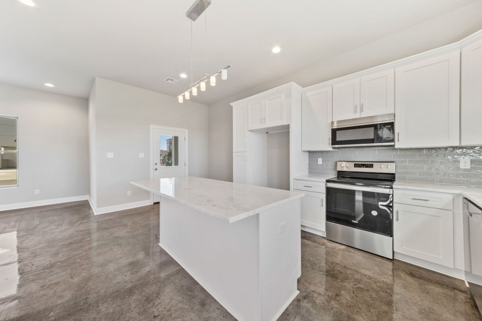 Bright, modern kitchen featuring white cabinetry, stainless steel oven, microwave, and spacious island in a new home. Perfect for cooking and entertaining.