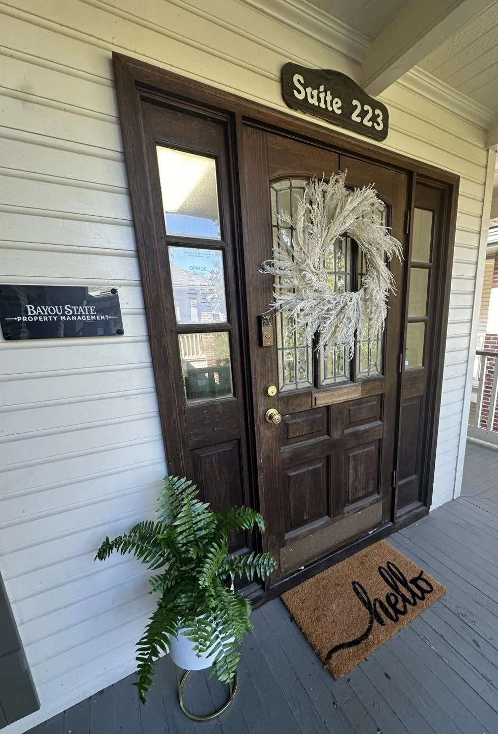 Front door of Bayou State Operations with decorative wreath and welcoming doormat, located at State 223.