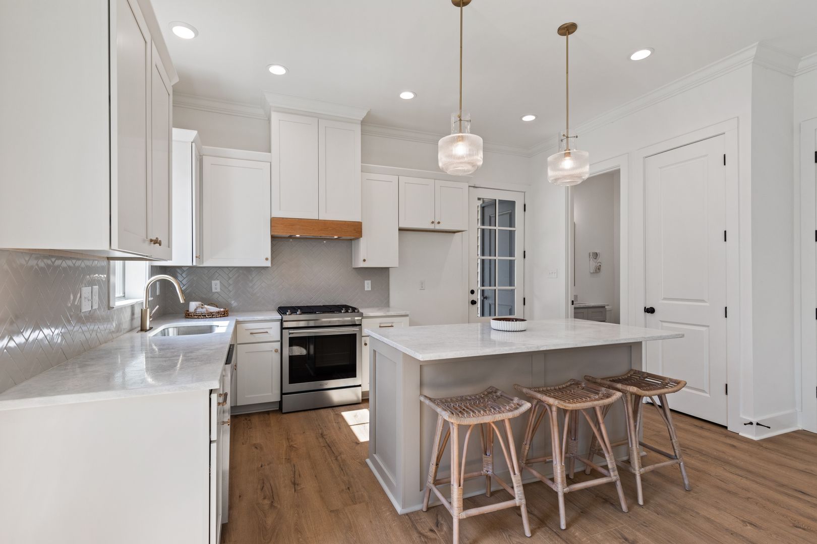 Bright modern kitchen featuring white cabinets, a central island with seating, stainless steel appliances, and pendant lighting, perfect for family living and entertaining.